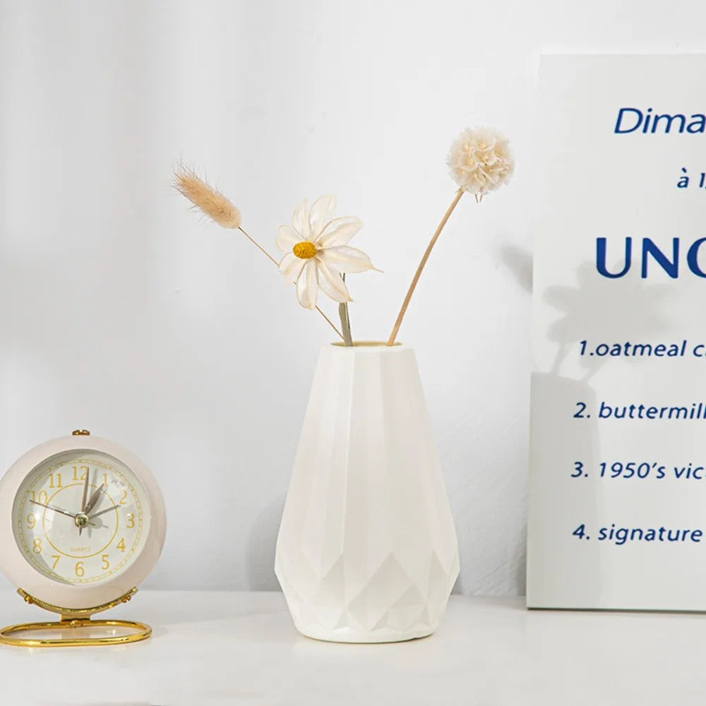 Minimalist Nordic-style diamond flower vase in white placed beside a golden desk clock