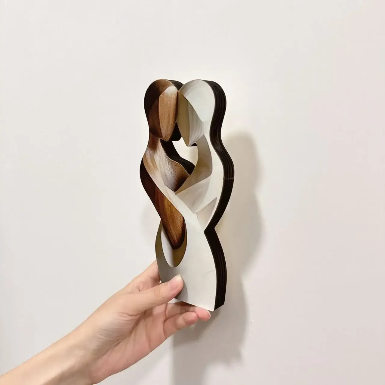 2D wooden couple statue held in hand showing side profile
