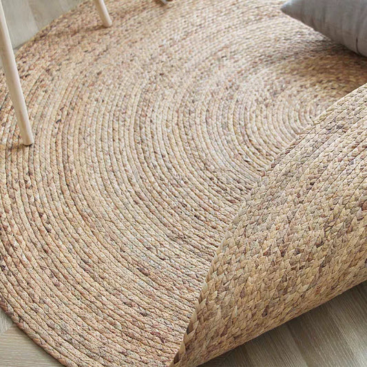 Close-up of hand-woven round straw rug showing natural reed weave and flexibility