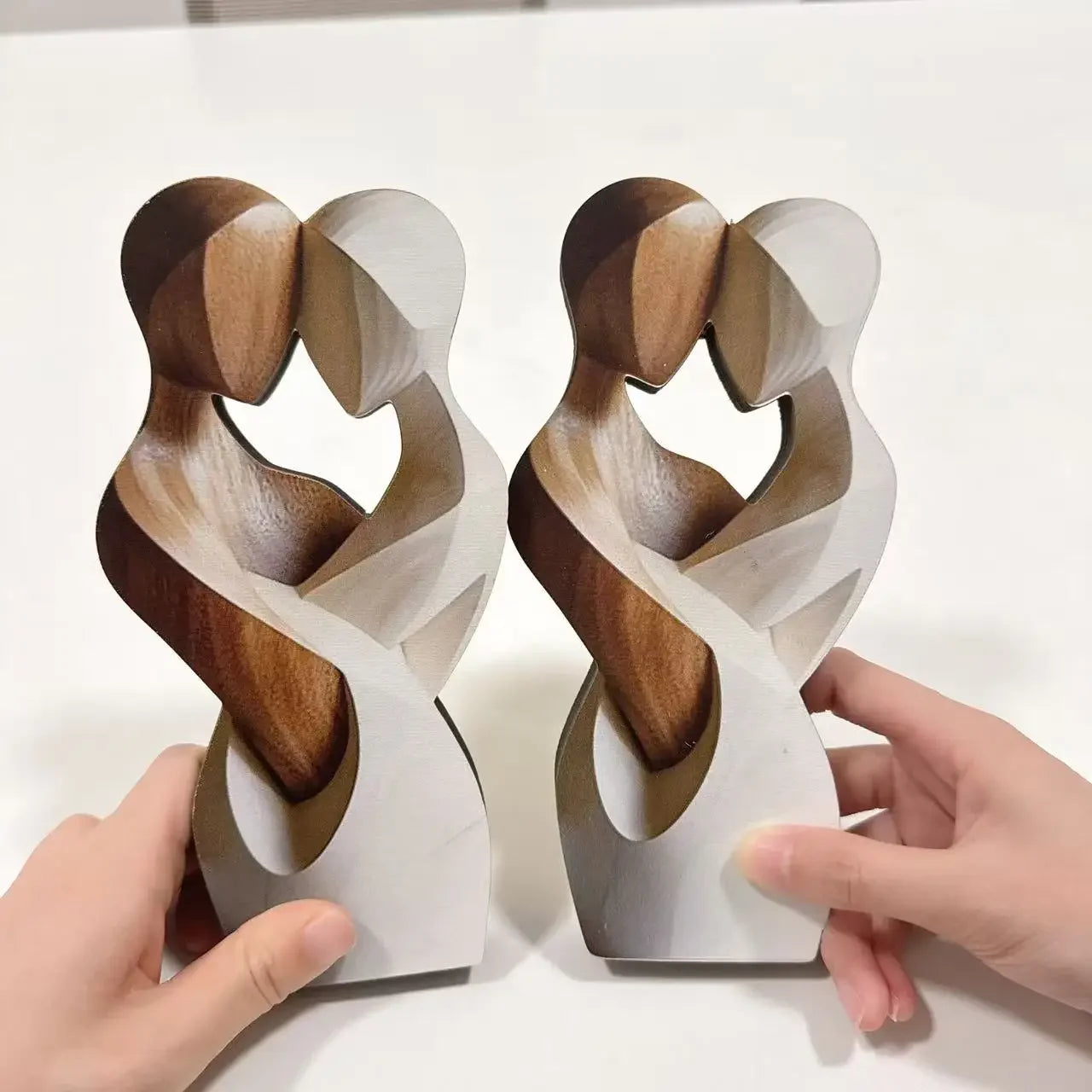 Pair of flat wooden couple sculptures in hand, side by side